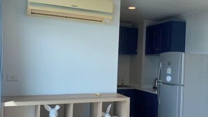 Una cocina con aire acondicionado integrado, armarios oscuros y un refrigerador.