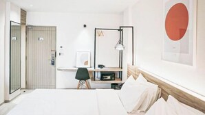 Une chambre d’hôtel moderne équipée d’un lit, d’un bureau, d’une chaise et d’une grande œuvre d’art murale.