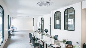 Une salle de conférence moderne, dotée d’une longue table, de chaises noires et de grandes fenêtres.