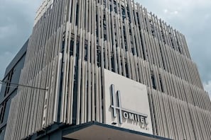 A modern hotel building with vertical lines, a prominent sign, and a clear sky. - Homitel Bangkok (Bangkok)