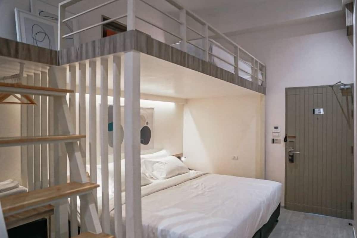 A single bedroom with a bunk bed, a wooden door, and a small desk with a chair.