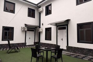 A courtyard with a table and chairs, air conditioning units, and a door. - zhongtian (Tashkent)