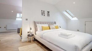A modern bedroom with a large bed, a skylight, and a view of the adjacent room. - Kula London - Fitzrovia Newman St (London)