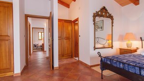 A bedroom with a bed, wooden doors, a mirror, and a nightstand with lamps.