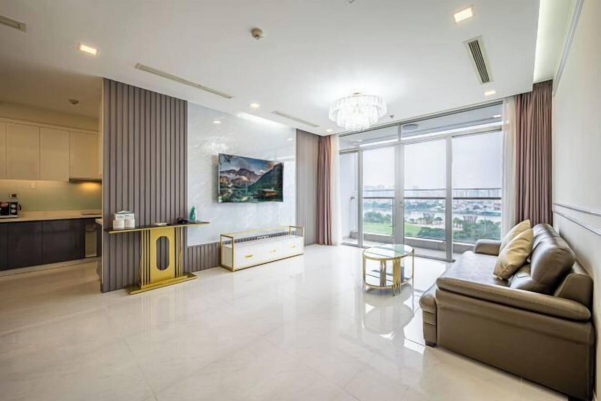 A modern living room with a sofa, a coffee table, and a large window offering a city view.