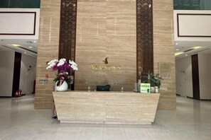 A reception desk with a floral arrangement, a sign with the name 'Vinegar's', and a potted plant. - VINHOMES APARTMENT LUXURY IN HCMC (Ho Chi Minh City)