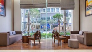 Een moderne lobby met een zithoek, grote ramen en binnenshuis planten.