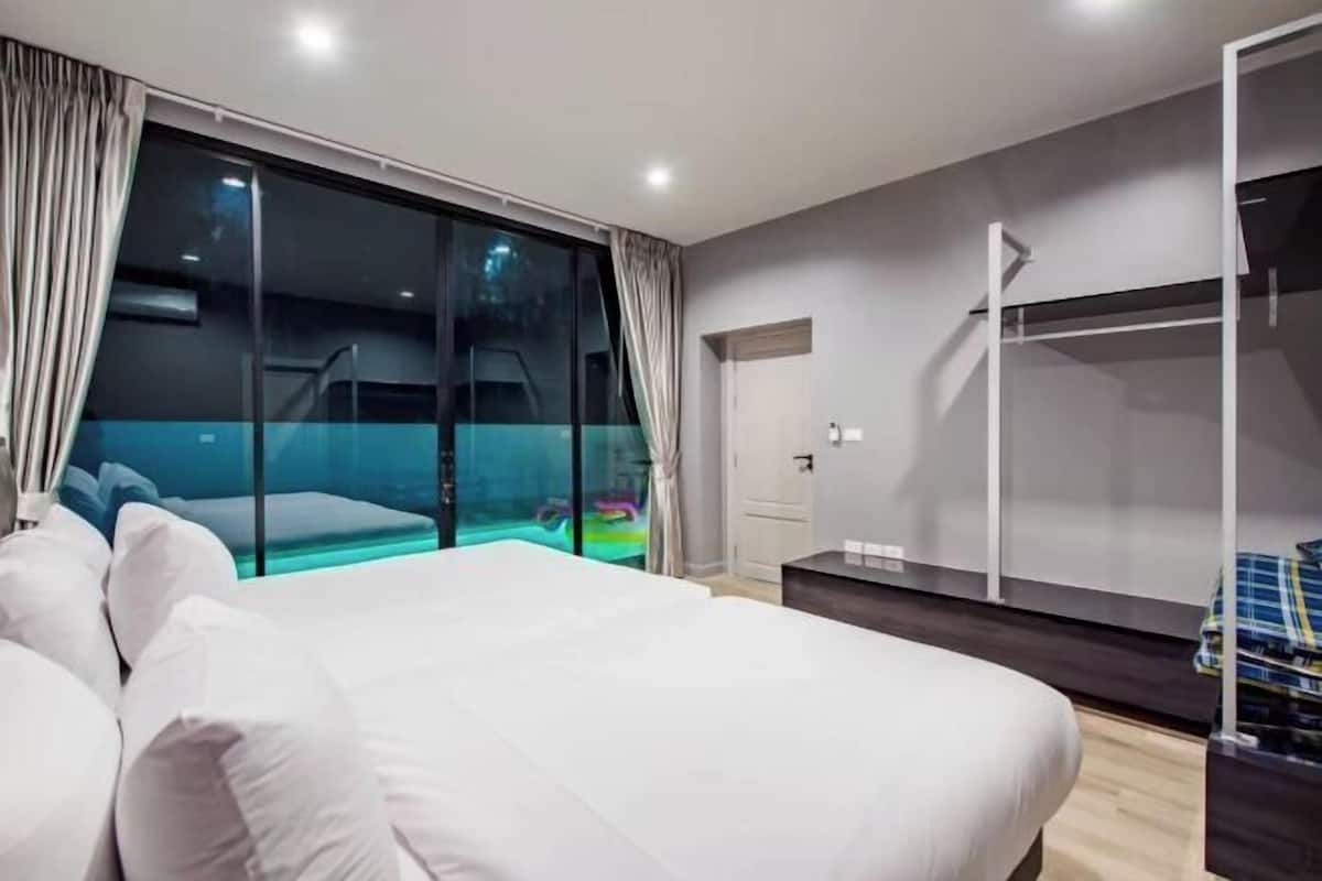 Quarto moderno com uma cama grande, porta de vidro que dá para uma varanda e um guarda-roupa.