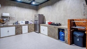 Eine Küche mit Betonwand, Edelstahlgeräten und einem Backofen aus Ziegeln.
