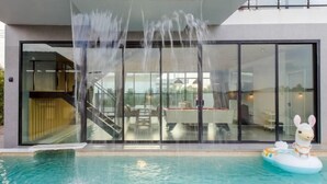 A modern building with a glass facade, a swimming pool, and a llama float. - Tantawan Poolvilla Huahin (Hua Hin)