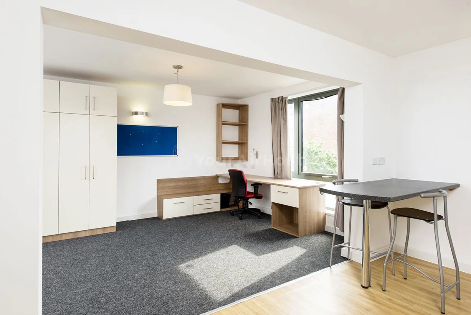 A modern, well-lit room with a desk, chair, and a small table.