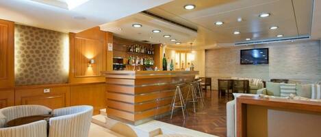 A bar area with a counter, stools, and a seating area with couches and chairs.
