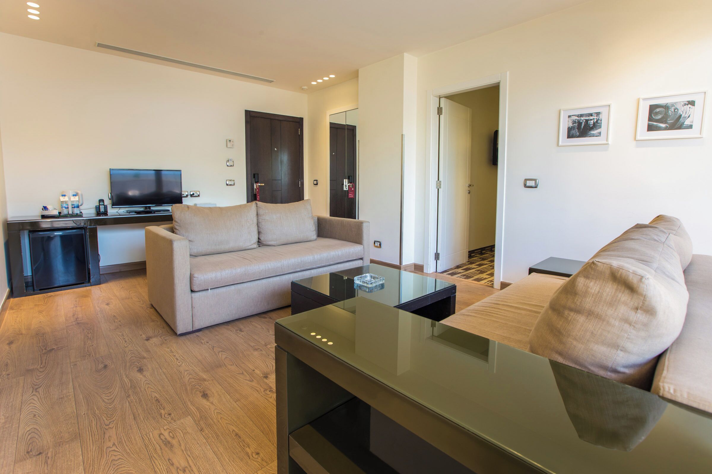 A modern living room with a sofa, a glass coffee table, and a television.