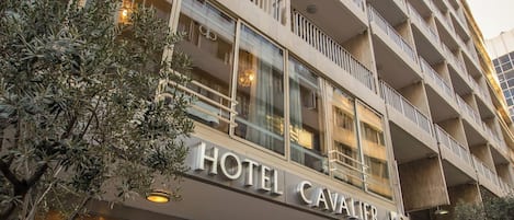 A multi-story hotel with balconies, a glass facade, and a sign reading 'HOTEL CAVALIER.'