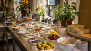 A buffet table with various food items and bowls, surrounded by potted plants. - Hotel Cavalier (Beirut)