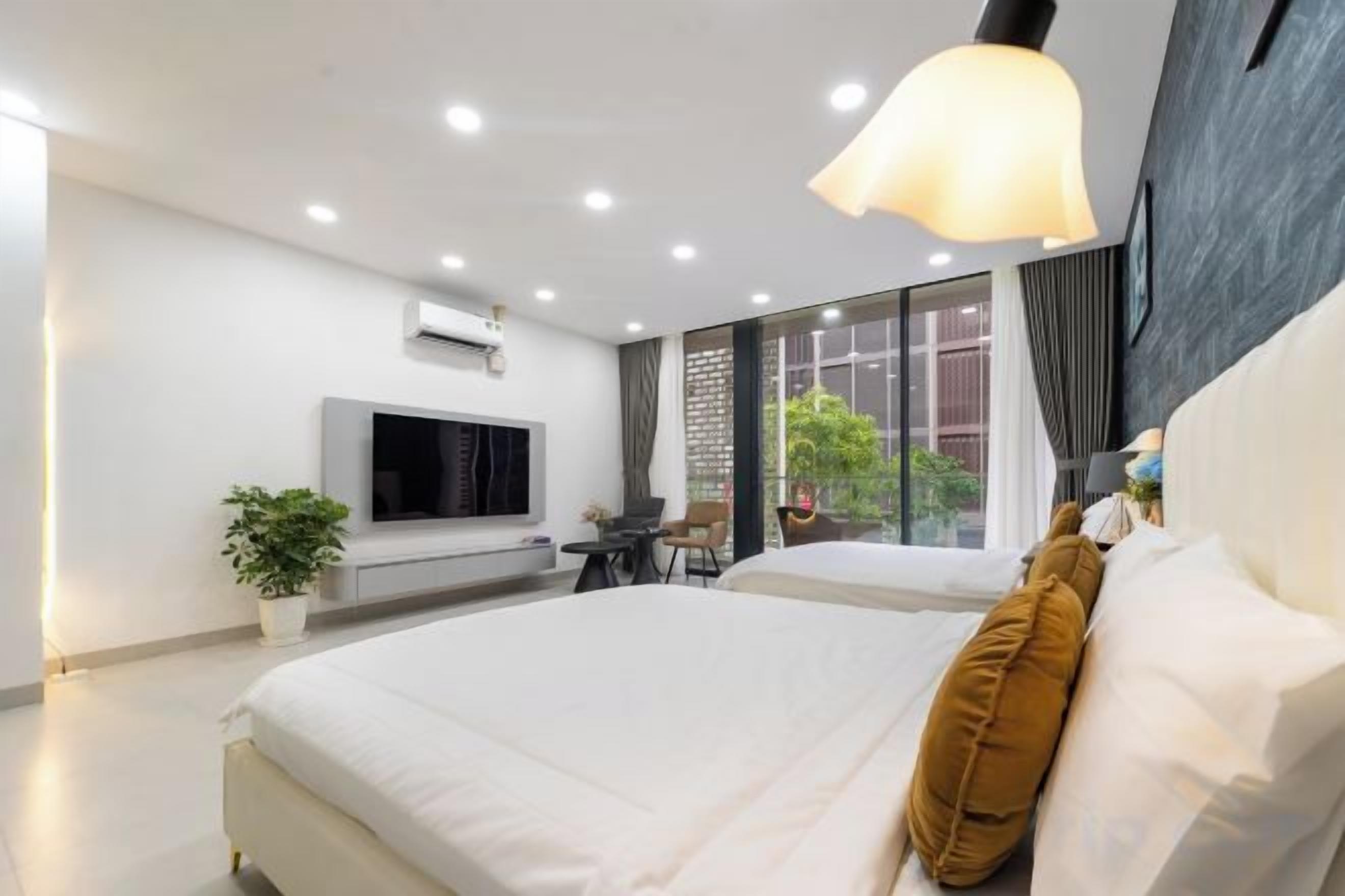 Een moderne hotelkamer met een groot bed, een flatscreen televisie, een bureau met stoel, en een groot raam met uitzicht op de omgeving.