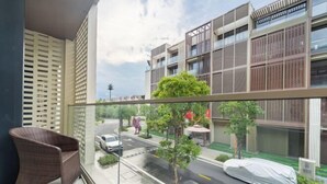Un balcon avec un fauteuil en osier, une vue sur une rue et un bâtiment sur lequel on peut lire l’inscription « HARBOR ».