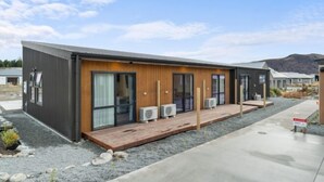 A modern building with a wooden deck, large windows, and air conditioning units. - Starlet 11 (Lake Tekapo)