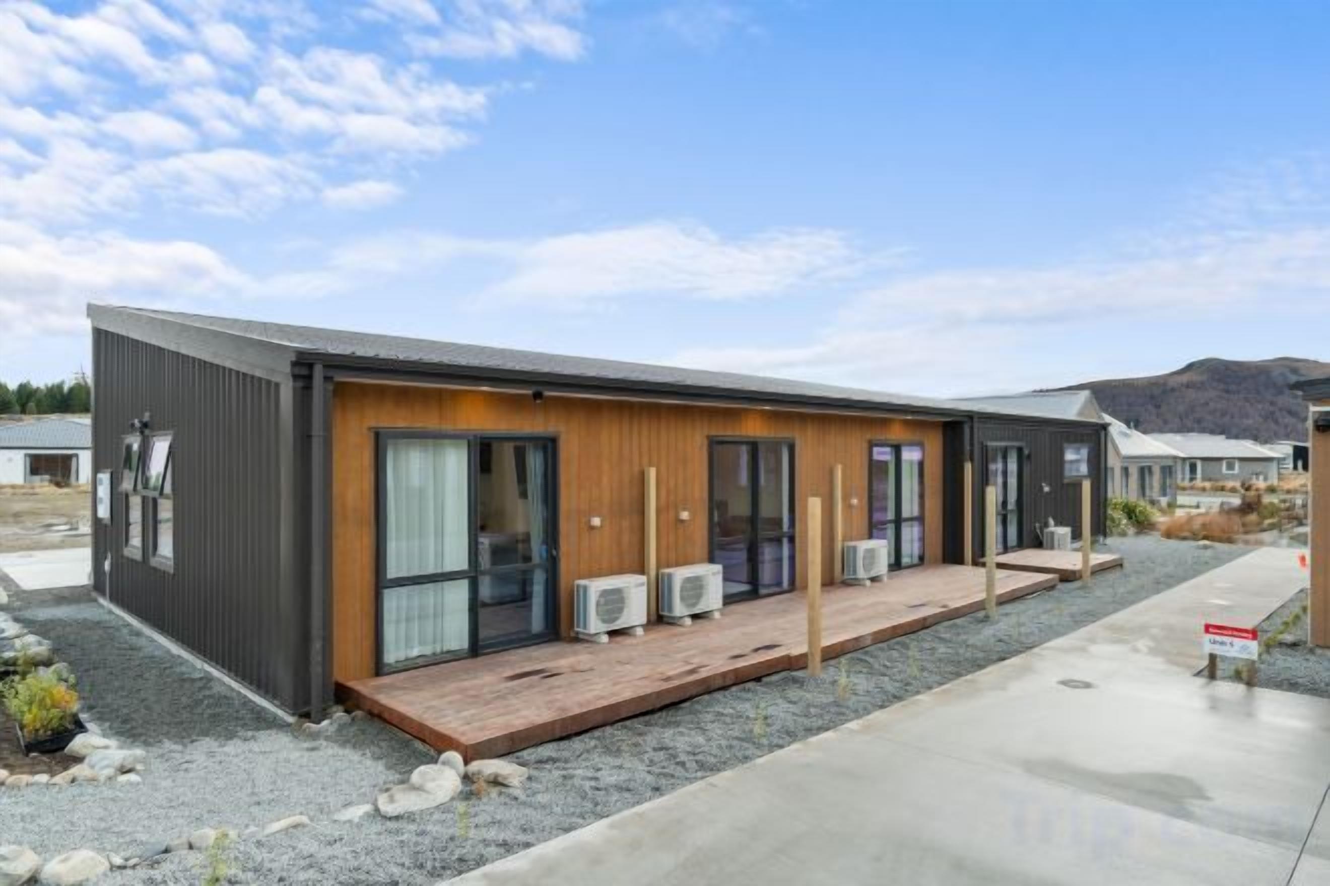 A modern building with a flat roof, large windows, and a wooden deck.