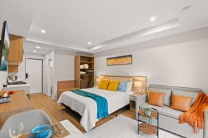 Una habitación de hotel moderna con cama, sofá y zona de comedor.