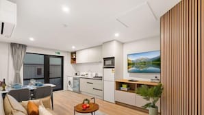 A modern hotel room with a sofa, dining table, kitchen area, and a large window. - Starlet 11 (Lake Tekapo)