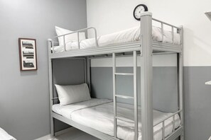 Een stapelbed met een klok aan de muur, een ingelijst beeld en een grijs-wit kleurenschema.