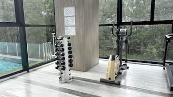 A gym with exercise equipment, a large window, and a view of trees.