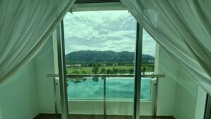 Uma varanda com porta de vidro, vista para montanhas e piscina.