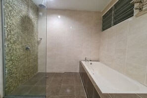 Une salle de bain avec une douche à parois de verre, une baignoire et des murs carrelés.