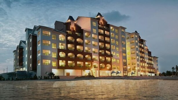 Hotel com vários andares e varandas, situado à beira-mar.