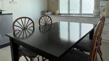A dining table with chairs, a kitchen area with cabinets, and a window.