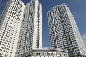 Ein Hochhaus mit einer geschwungenen Struktur am Sockel, mehreren Etagen und blauem Himmel.