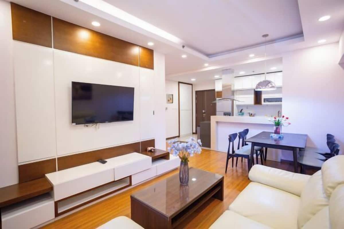 Ein modernes Wohnzimmer mit Flachbildfernseher, einer Couch, einem Couchtisch und einem Essbereich mit Stühlen.