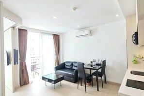 A modern living room with a sofa, dining table, chairs, and a coffee table. - City Garden Olympus Condominium 1room (Pattaya)