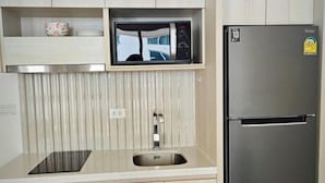 Una cocina con refrigerador de acero inoxidable, microondas integrado y pileta.