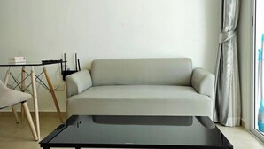 Una sala moderna con un sofá de color claro, una mesita y una silla.