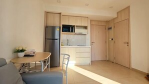 Una cocina compacta con refrigerador, microondas y armarios de madera.