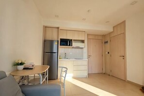 A compact kitchen with a refrigerator, microwave, and wooden cabinets. - City Garden Olympus Condominium 1room (Pattaya)