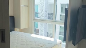 Un dormitorio con cama, televisión y ventana con vistas a balcones.