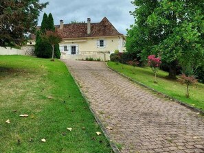 A cobblestone path leading to a building with a pitched roof and white walls.