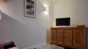 Un salon chaleureux avec un meuble en bois, un téléviseur à écran plat et un tableau encadré accroché au mur.