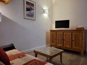 Uma sala de estar acolhedora com um armário de madeira, uma televisão de tela plana e um quadro na parede.