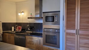 Une cuisine moderne dotée d’appareils électroménagers en acier inoxydable, de meubles en bois et d’un four encastré.