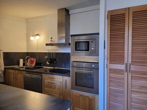 Uma cozinha moderna com eletrodomésticos de aço inoxidável, armários de madeira e forno embutido.