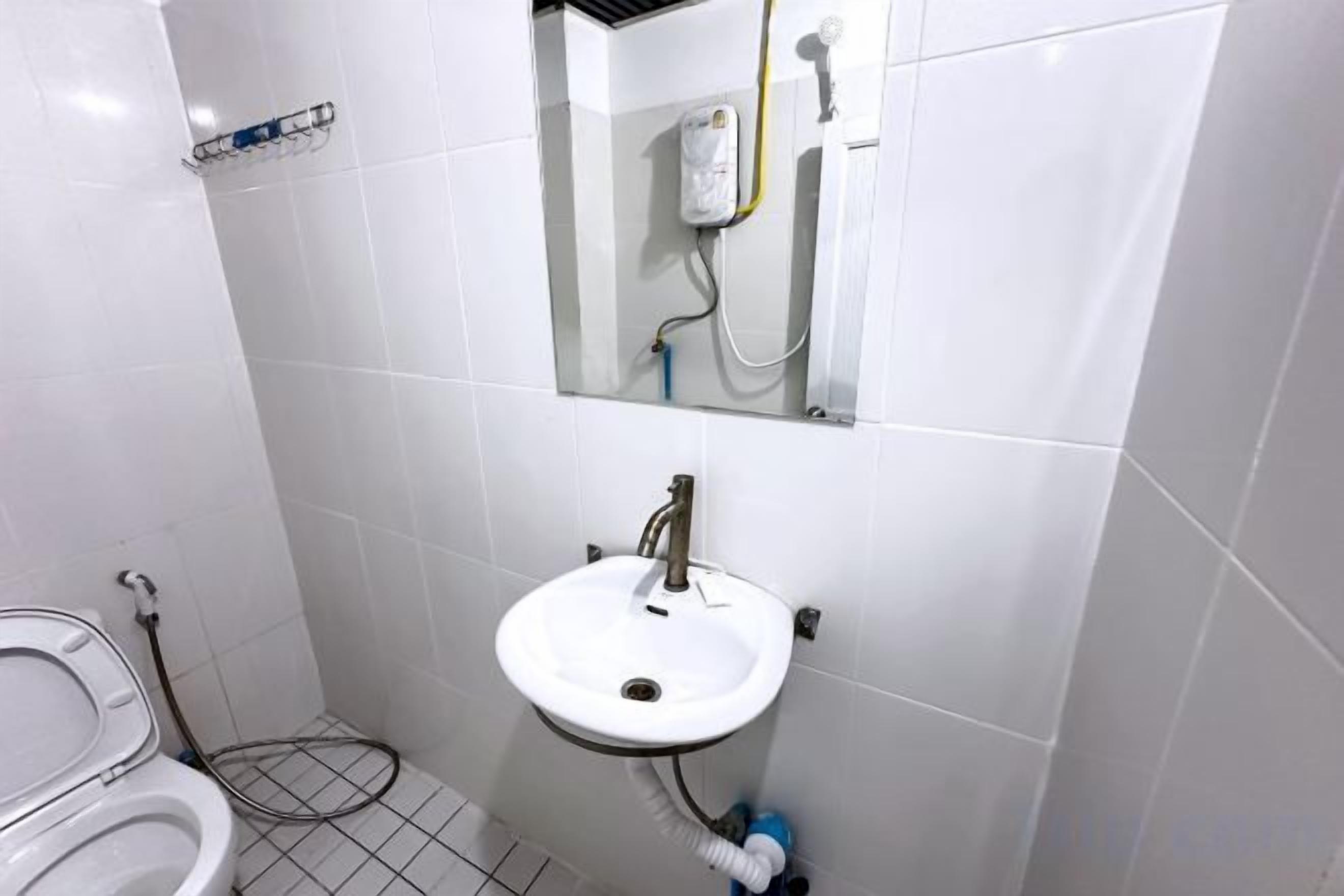 Un baño con lavamanos, espejo y retrete blancos.