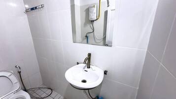 Un baño con lavamanos, espejo y retrete blancos.