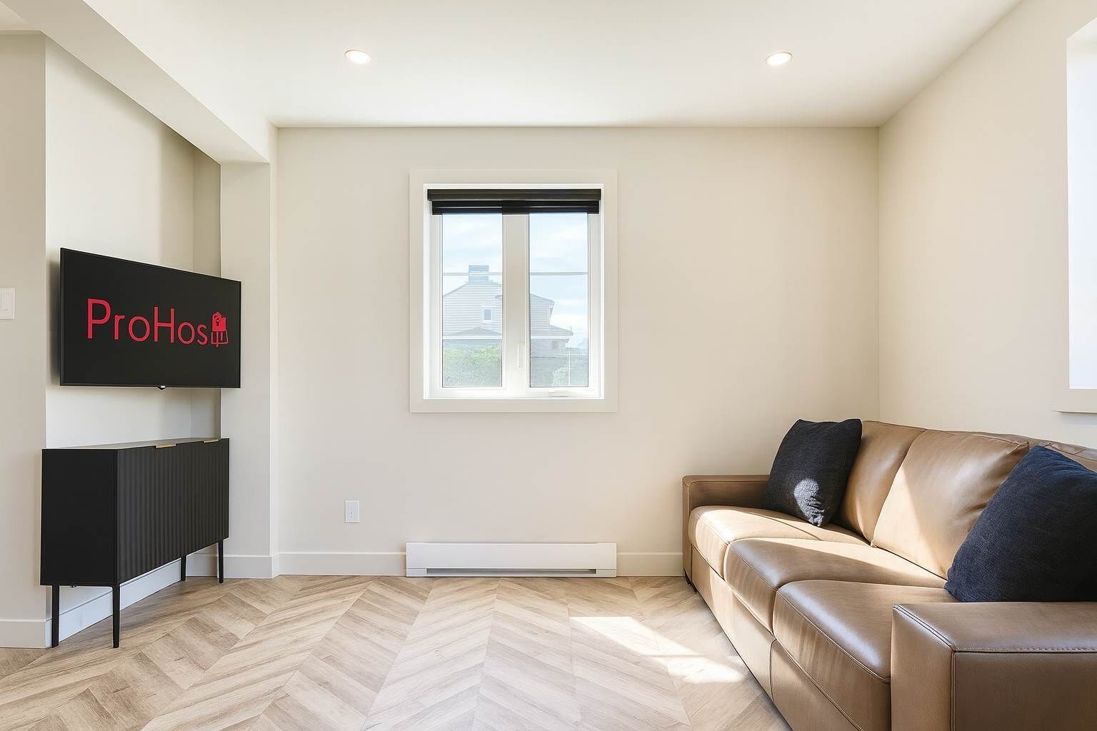 A modern living room with a beige sofa, a black entertainment unit, and a large window.