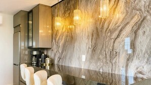 A modern kitchen with a marble backsplash, stainless steel appliances, and a glass dining table with white chairs. - Luxe & détente | 1 ch • 4 pers • Spa •Free Parking (Boischatel)