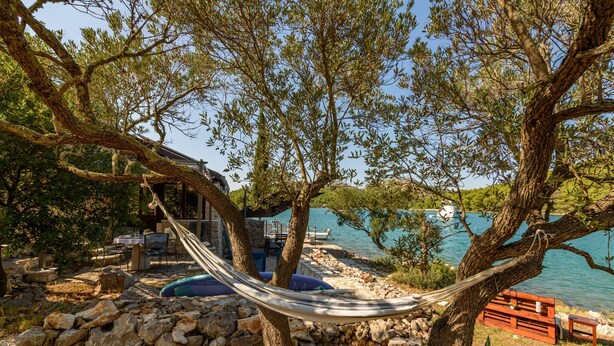 A hammock between trees overlooking a lake with a rustic outdoor seating area. - Zadarvillas Off-grid Private Island Retreat (Sali)