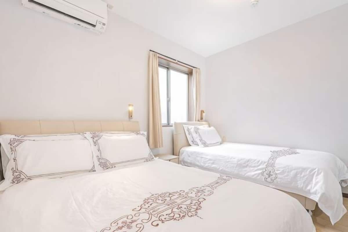 Een hotelkamer met twee bedden, een raam en een airconditioning.